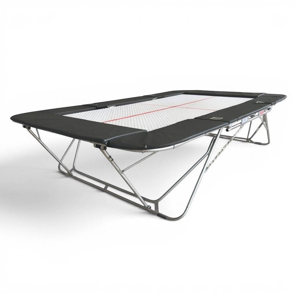 UK Gym Pits 77a standard competition trampoline with a 25mm web bed and black protective frame pads.