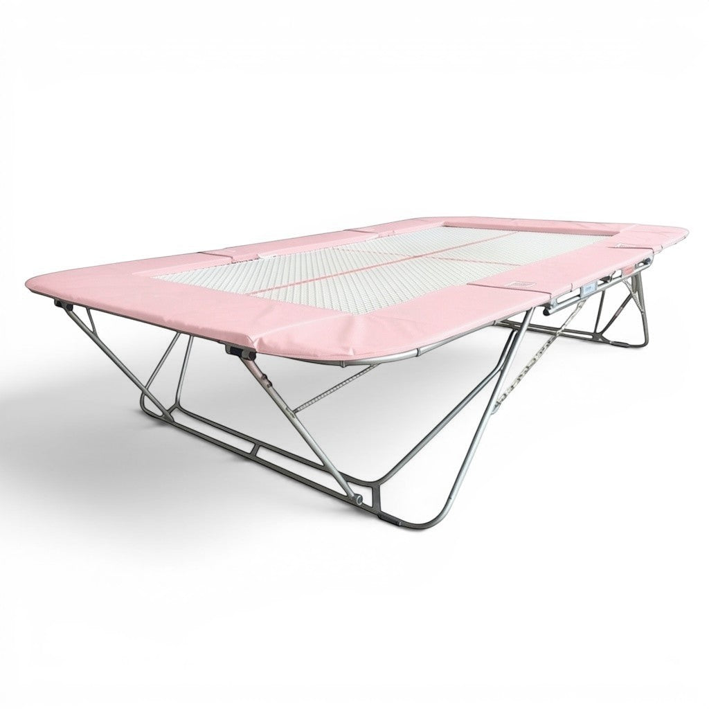 UK Gym Pits 77a standard trampoline with a pink frame pad and 25mm web bed for gymnastics and competition training.