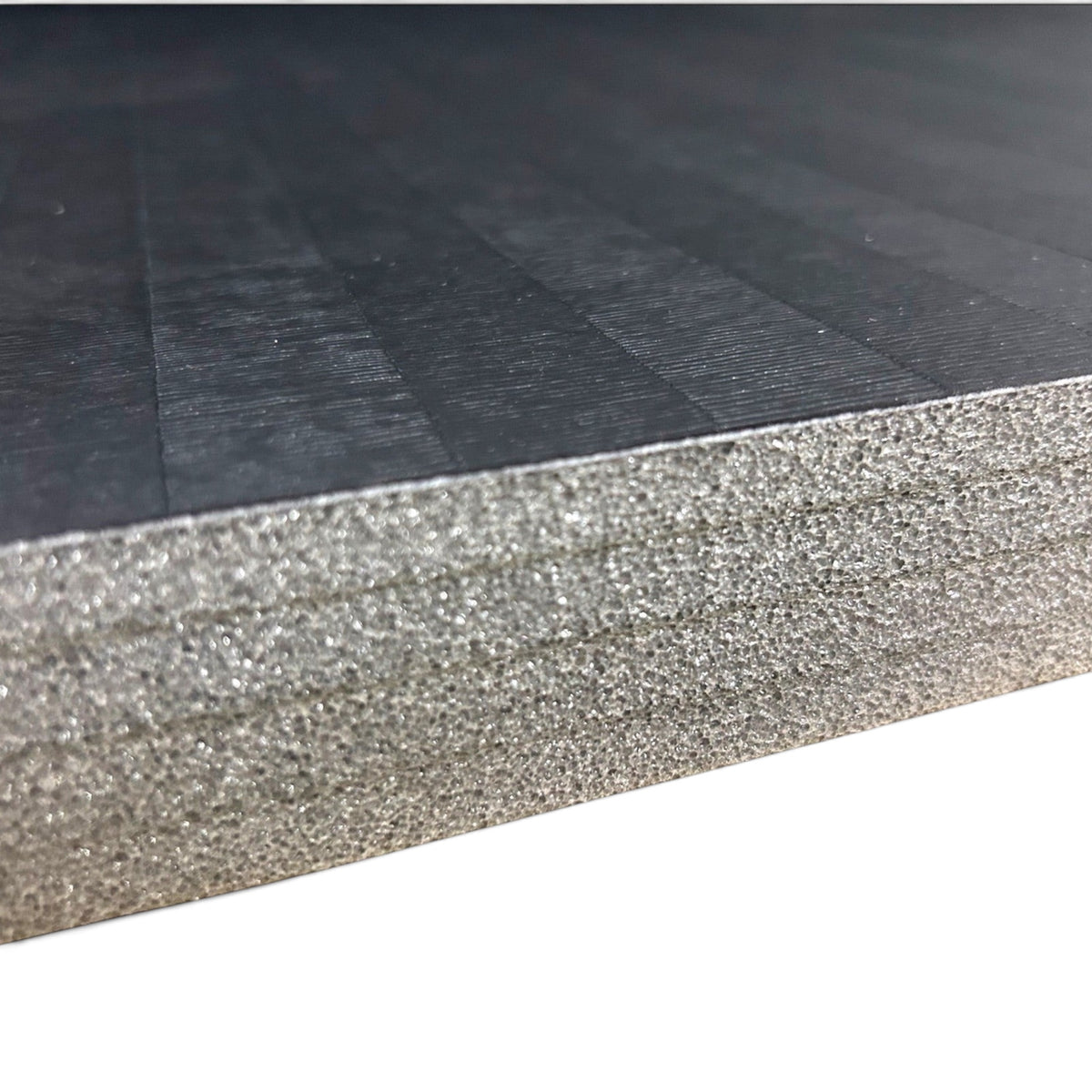 UK Gym Pits black hybrid gymnastics mat roll showing the durable tatami PVC surface and shock-absorbing XPE foam core.