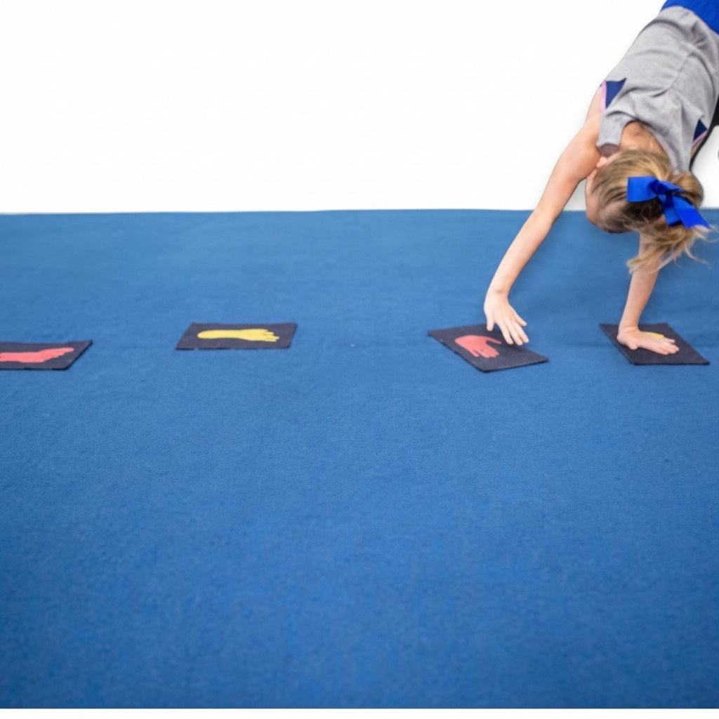 UK Gym Pits gymnastics markers with red and yellow hand and foot prints on blue mat during a handstand practice