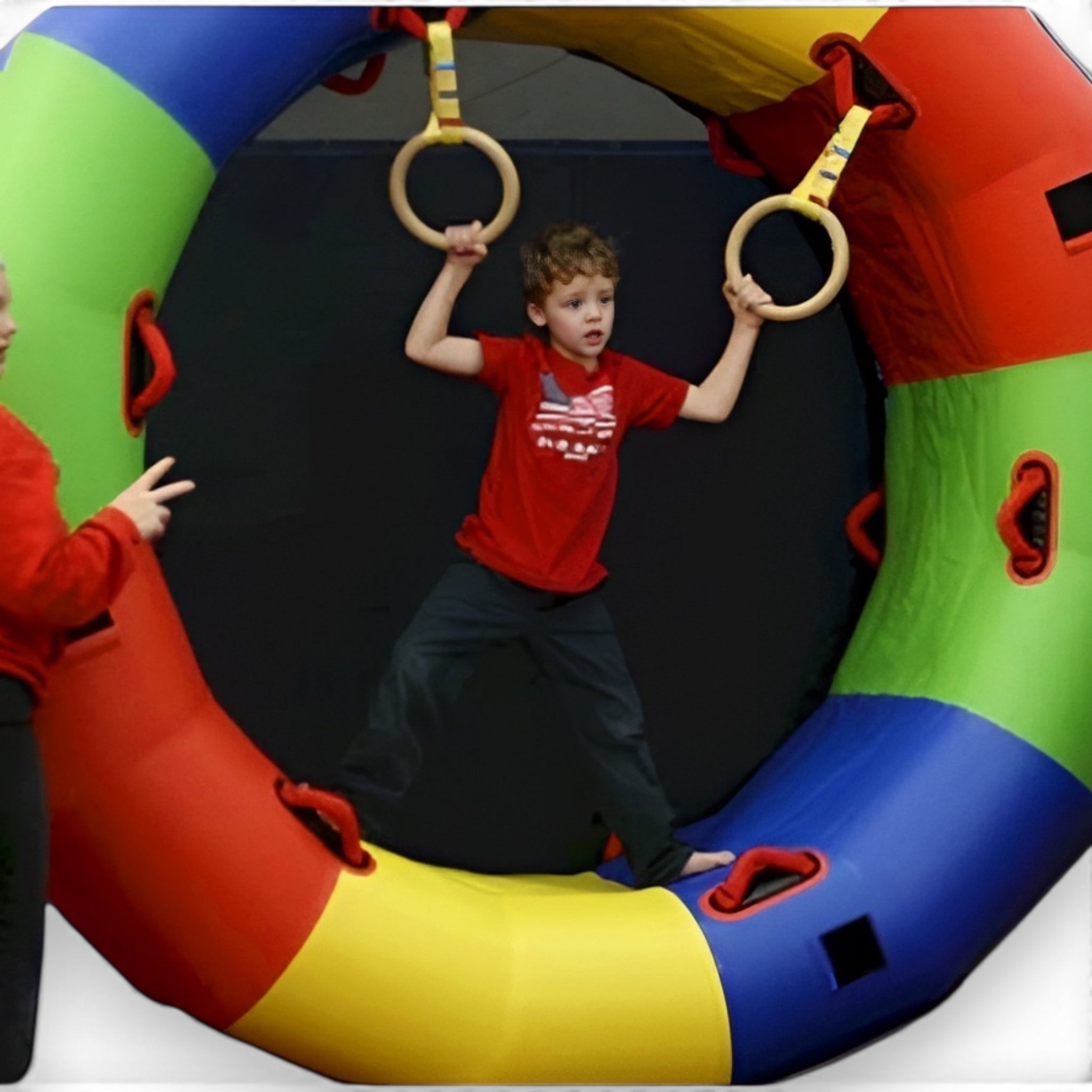 UK Gym Pits gymnastics rings held by a child standing on a large colourful padded circular training mat