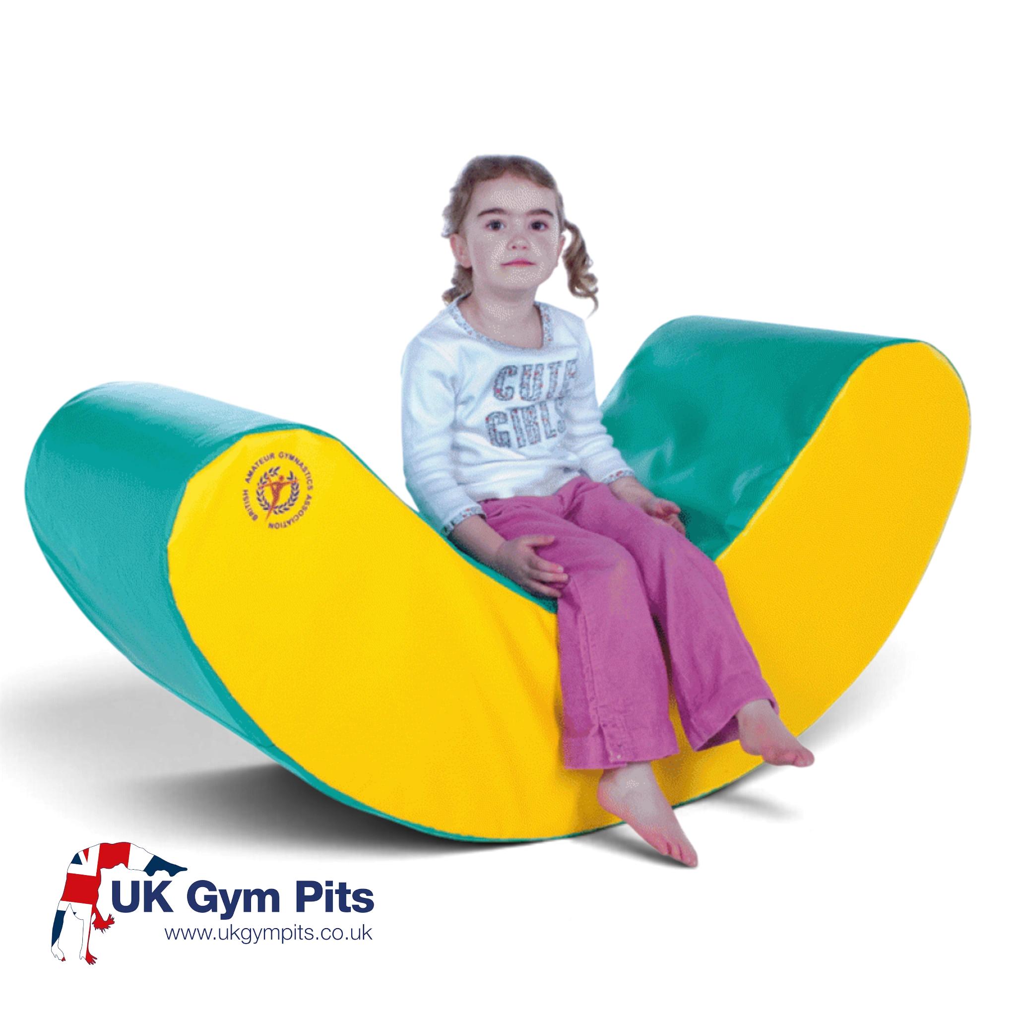 A young girl sitting on a UK Gym Pits green and yellow foam rocker, designed for soft play and motor skill development.