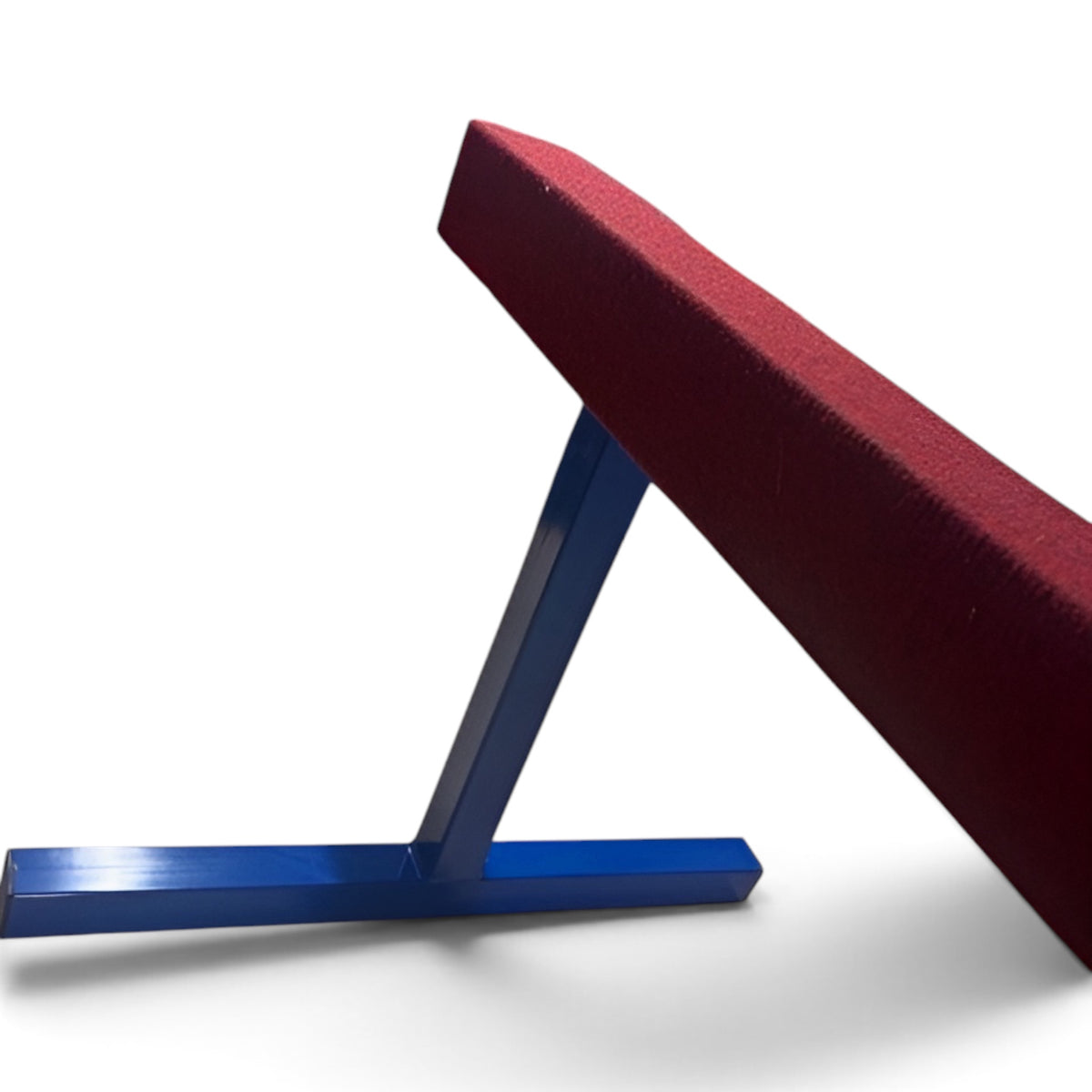 UK Gym Pits raised gymnastics training beam with a red carpeted surface and blue powder-coated steel legs.