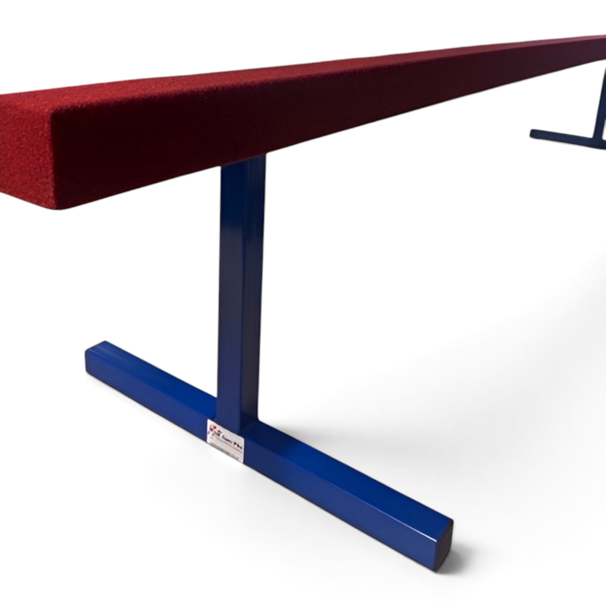 UK Gym Pits raised training balance beam with a red carpeted surface and blue powder-coated steel legs.