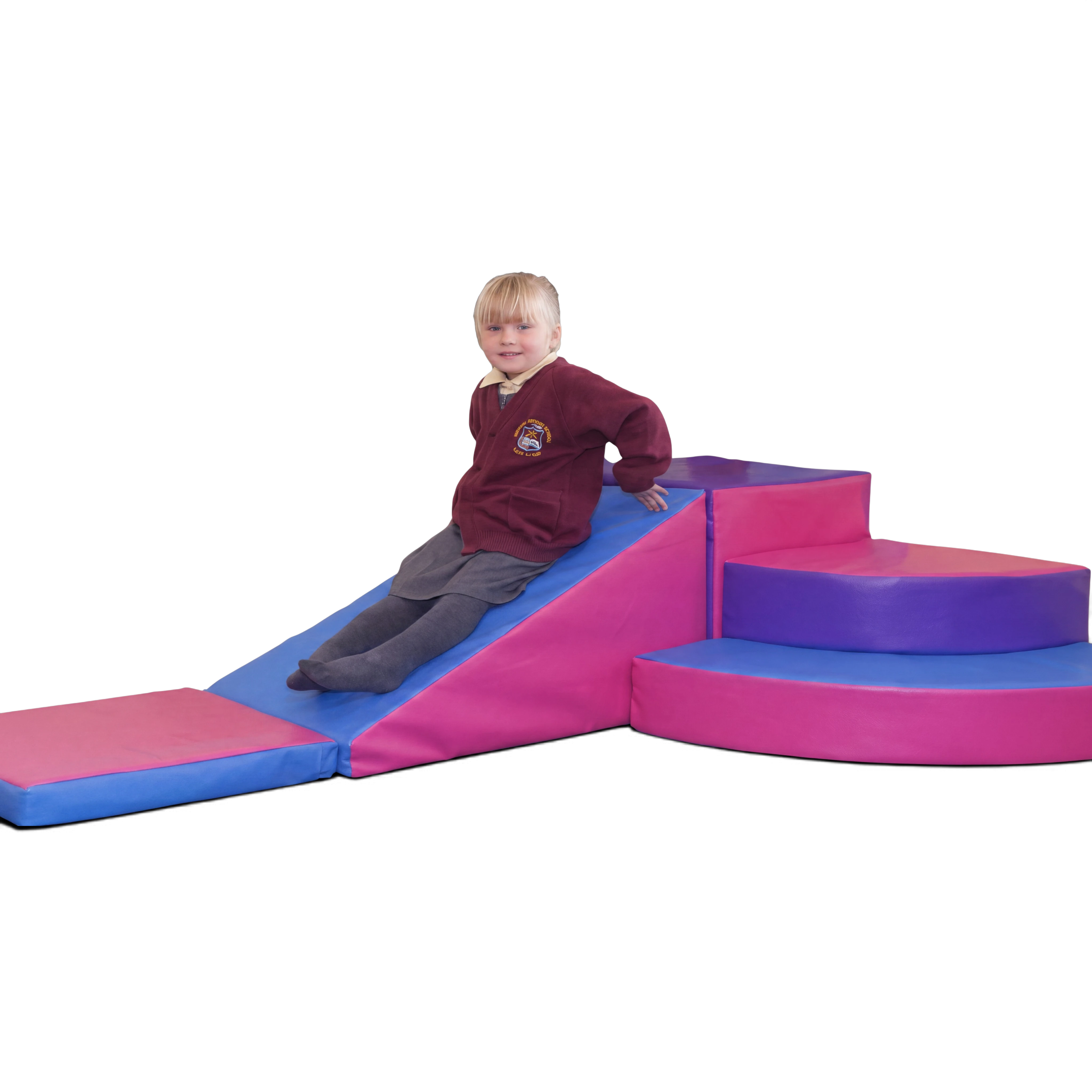 A child sitting on a UK Gym Pits soft play corner set featuring pink and blue foam steps, a slide, and a floor mat.