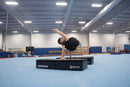 Person performing a gymnastic routine on a booster block pro in a gym setting.