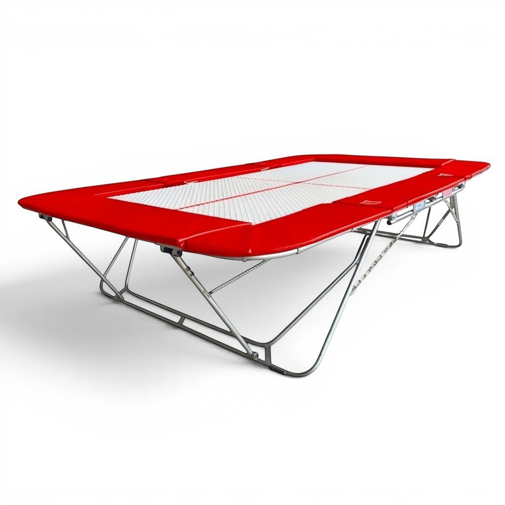 UK Gym Pits 77a standard competition trampoline with a white 25mm web bed and bright red protective frame pads.