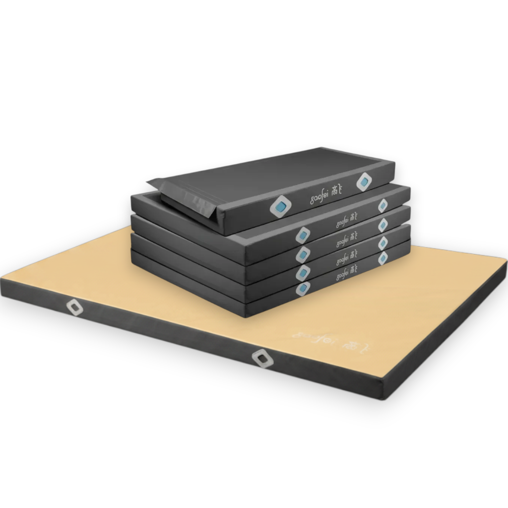 UK Gym Pits FIG approved asymmetric bars landing mats with black PVC sides and a tan top surface in a stacked arrangement.