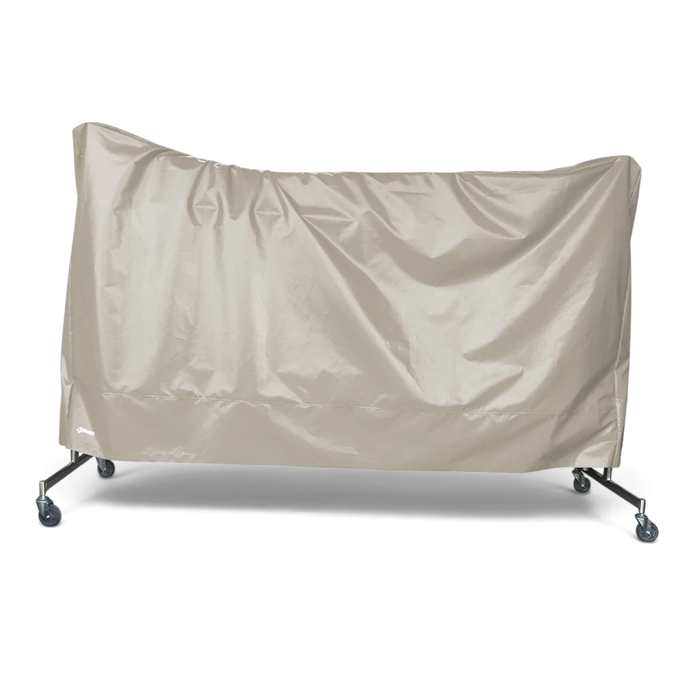 UK Gym Pits beige tear-resistant PVC dust cover protecting a folded trampoline on wheels against a black background.