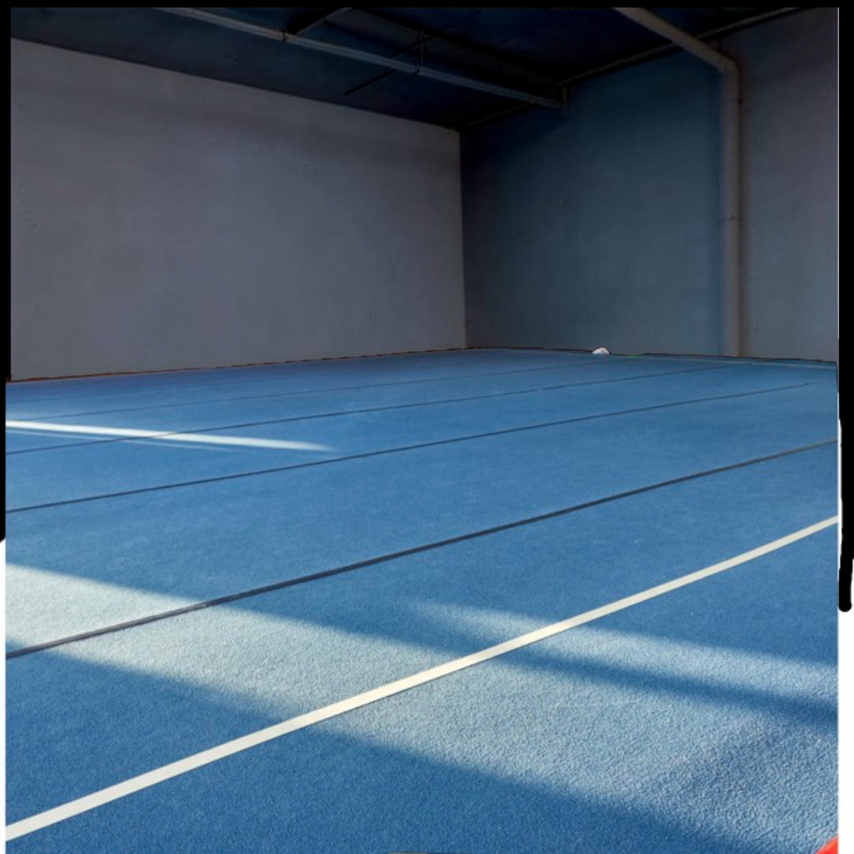 UK Gym Pits blue carpeted cheerleading sprung floor installed in a training facility with white boundary lines.