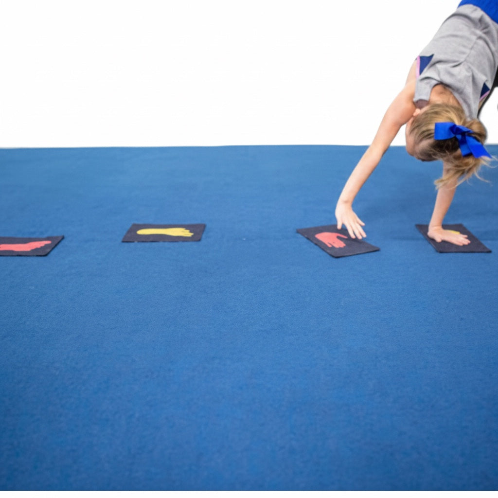 UK Gym Pits Hands & Feet denim markers with red and yellow prints on a blue gym mat for gymnastics training
