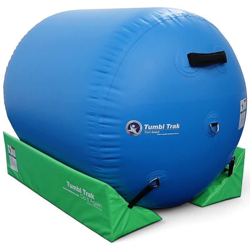 UK Gym Pits lime green foam cradle stabilizing a large blue inflatable air barrel for gymnastics training