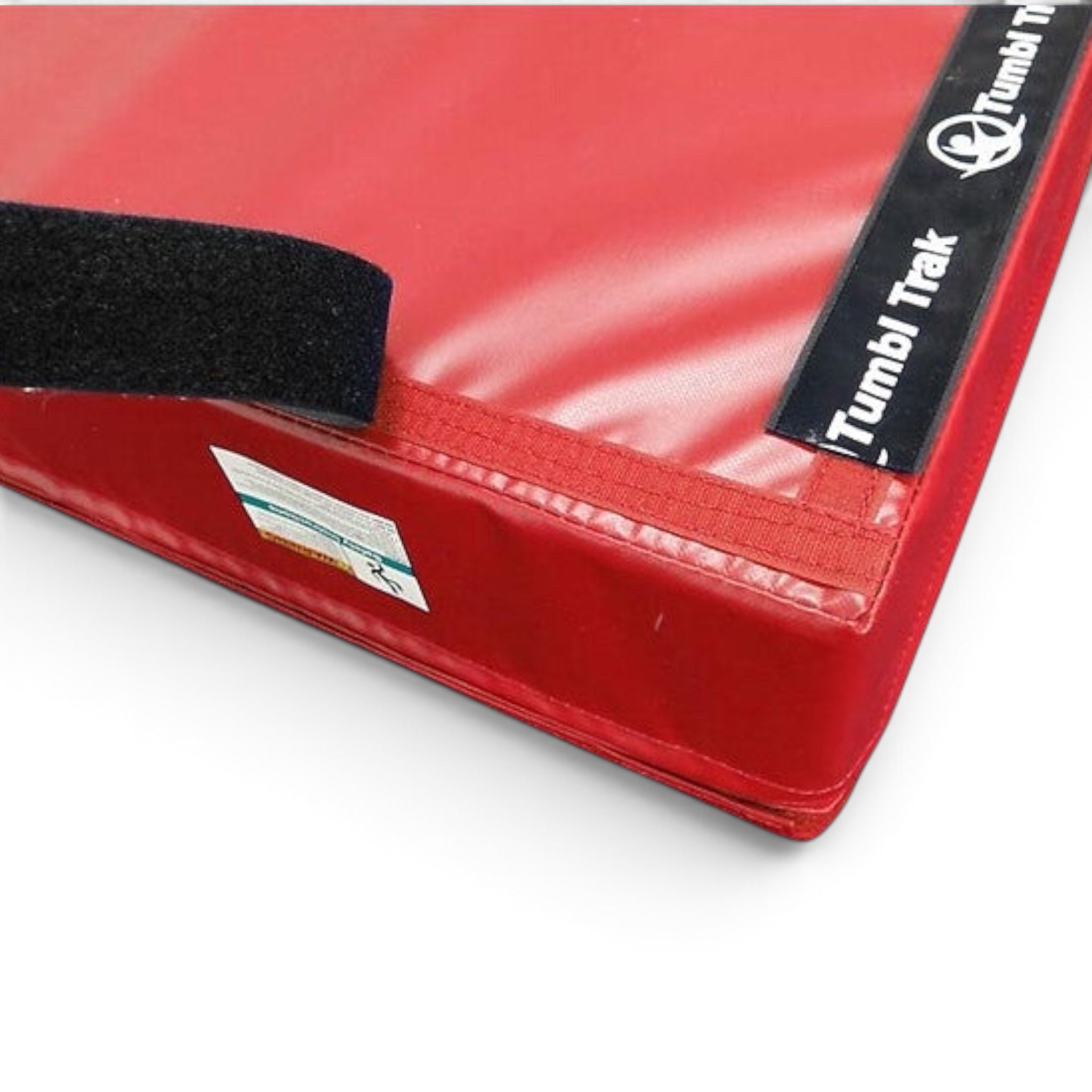 UK Gym Pits black non-slip loop Velcro strip being applied to the edge of a red gym mat to prevent sliding.