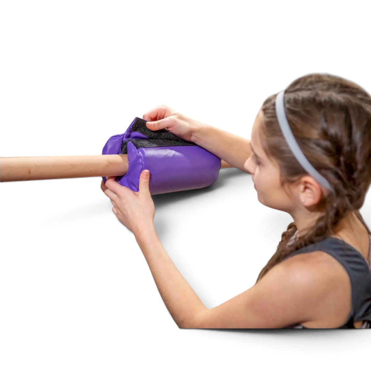 A young gymnast attaching a purple UK Gym Pits vinyl bar pad with Velcro closure to a training bar for comfort.