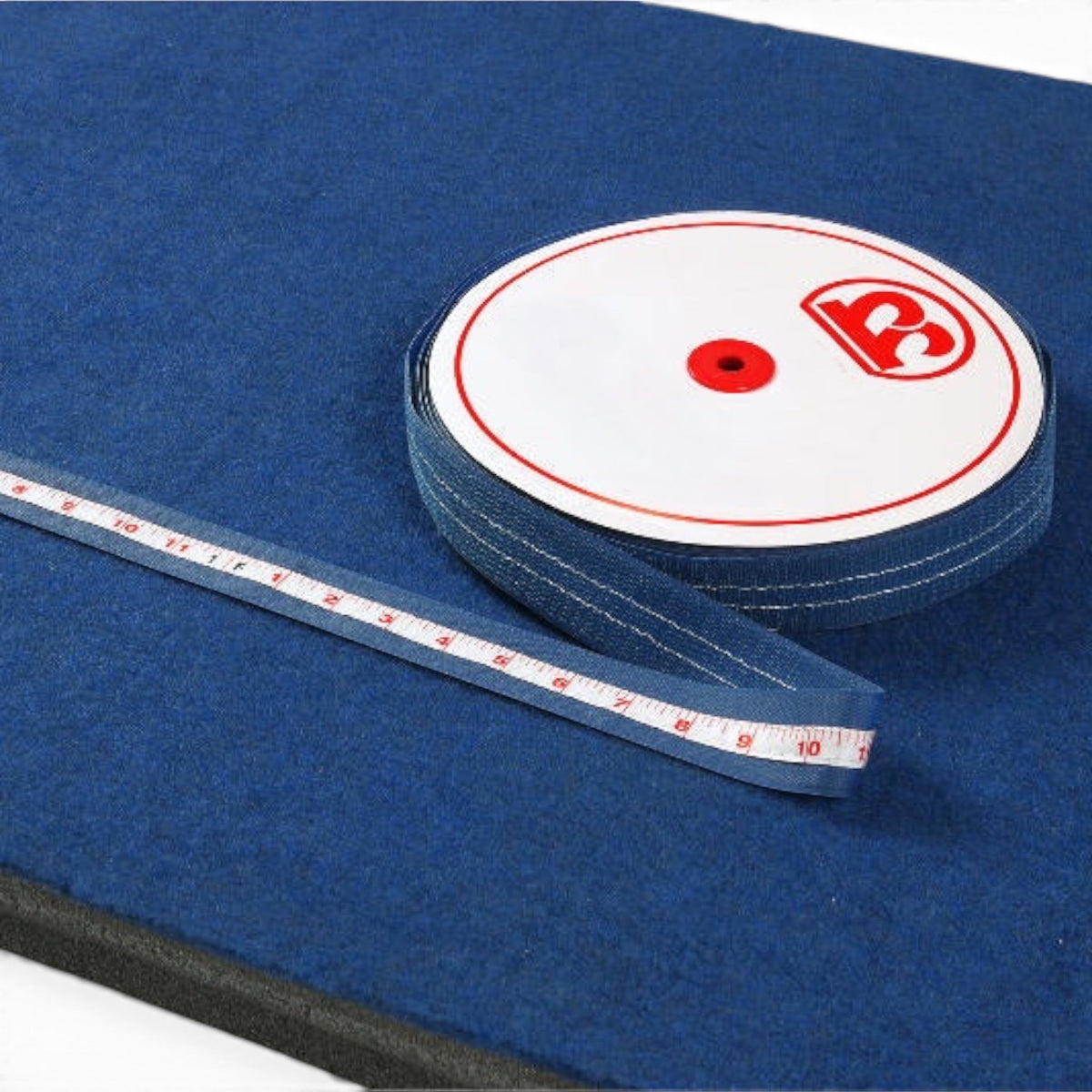 UK Gym Pits runway tape measure with Velcro backing on a blue carpeted surface for gymnastics training