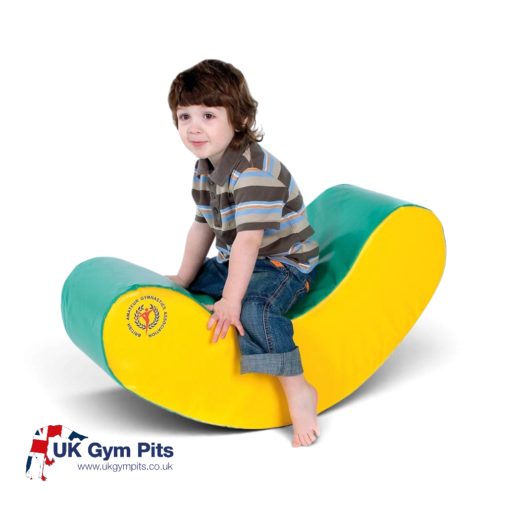 UK Gym Pits small green and yellow foam rocker for children to sit and play on, promoting gross motor skills.