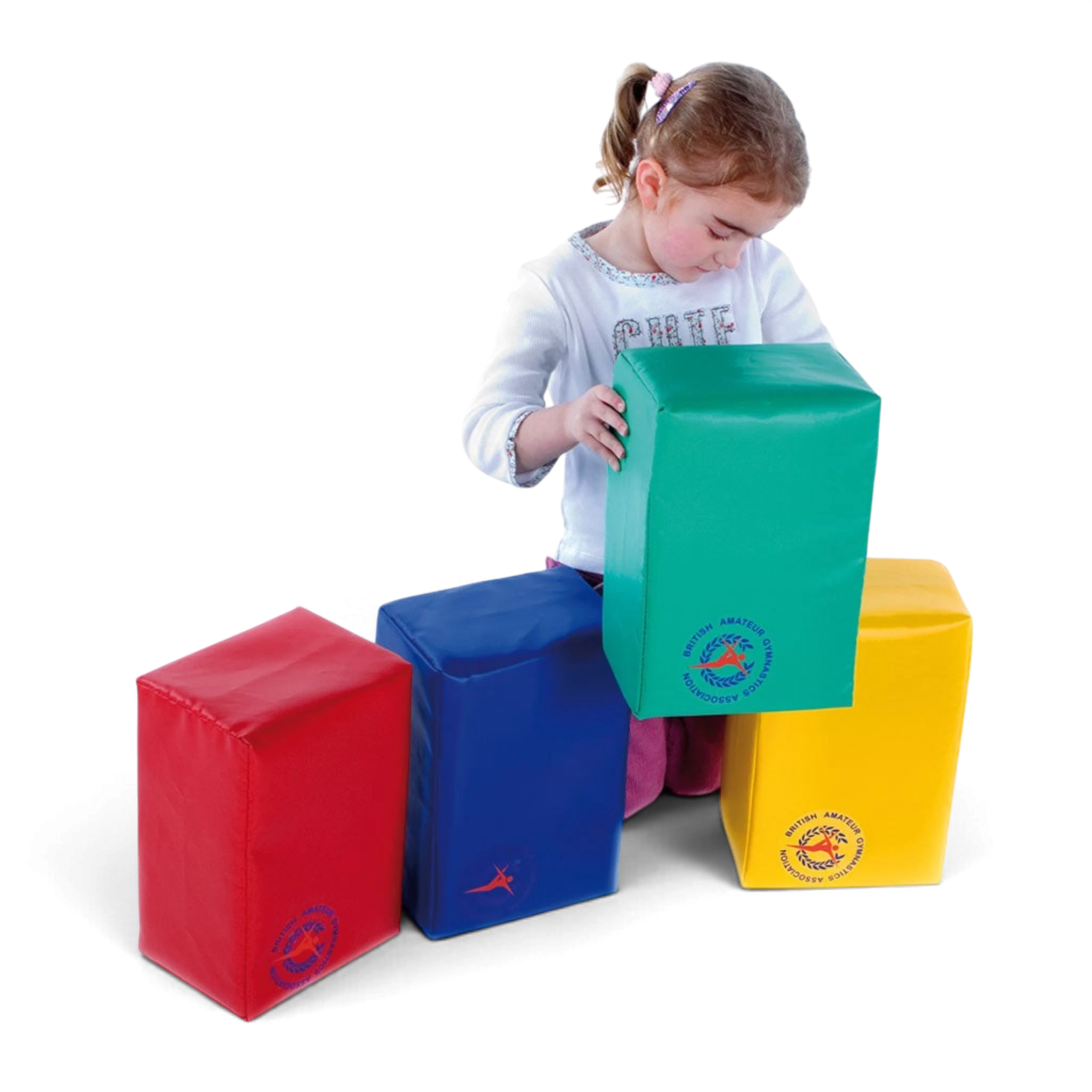 Young girl playing with UK Gym Pits soft play foam blocks in red, blue, green, and yellow for gross motor development.
