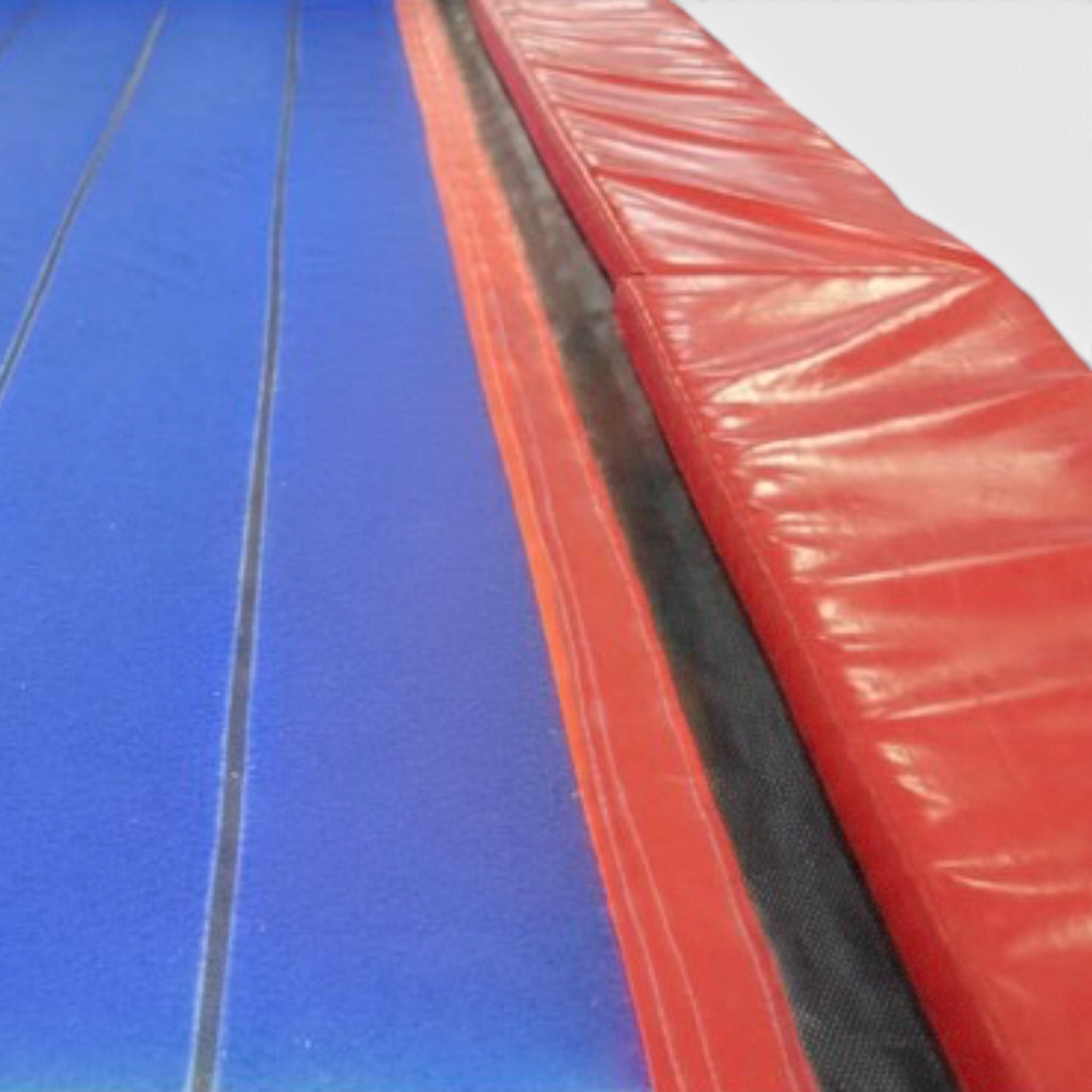 UK Gym Pits Tumbl Trak Transition featuring a blue carpet-like surface, white center line, and protective red side pads.